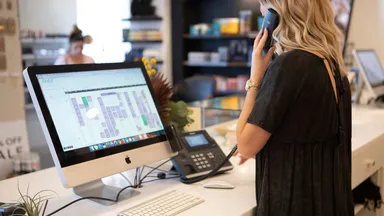 woman on phone at desk using software